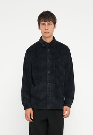 Black checkered flannel shirt with button closure, single chest pocket, and long sleeves. Soft texture and relaxed fit.