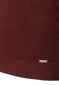 Bordeauxfarbener Pullover mit geripptem Struktur und einem kleinen Metalllabel mit "MORE & MORE", das am Saum angenäht ist. Weiches Strickmaterial.