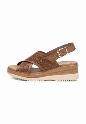 Sandalias de cuña de cuero marrón con tiras cruzadas, perforaciones florales, correa ajustable en el tobillo y suela de goma para mayor tracción.
