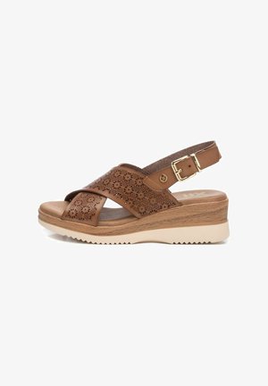 Sandalias de cuña de cuero marrón con tiras cruzadas, perforaciones florales, correa ajustable en el tobillo y suela de goma para mayor tracción.