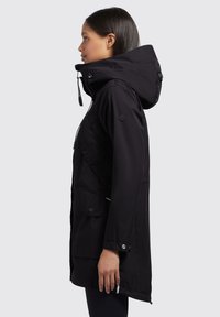 Veste parka noire avec capuche, fermeture éclair à l'avant, poches latérales et boutons-pression. Fabriquée dans un tissu lisse et durable.