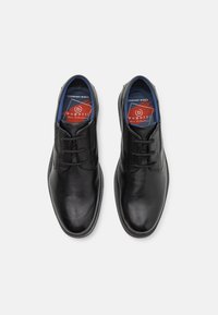 Czarne skórzane buty z gładkim wykończeniem, zaokrąglonym noskiem, wiązanym designem oraz niebieskim wnętrzem z czerwonym logo. Lekka podeszwa.