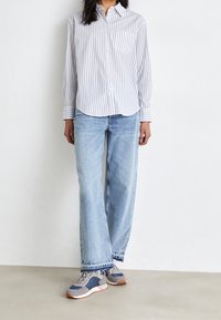 Proužkovaná košile na knoflíky v světle modré a bílé barvě; kombinovaná se světle modrými širokými džíny a šedými teniskami s námořnickými akcenty a texturovanou podrážkou.