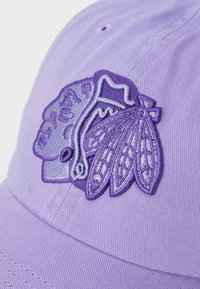 Cappellino da baseball viola con un design ricamato testurizzato che presenta un'ala stilizzata e un logo, dettagli con filo a contrasto e una forma strutturata.