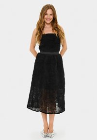 Rochie neagră fără bretele, cu un design floral texturat, un corset ajustat și o fustă fluidă. Accentuată cu un cordon solid negru.