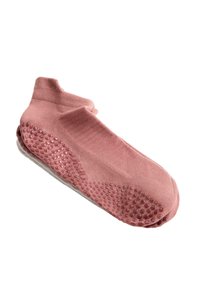 Chaussettes roses montant à la cheville avec des points en caoutchouc sur la semelle pour un maintien antidérapant, posées à plat sur un fond blanc.