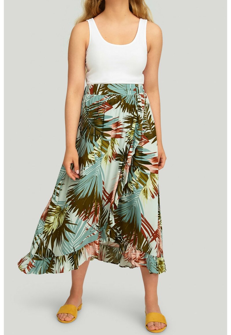 Jupe longue en tissu bleu clair avec un motif de feuilles tropicales en vert, rose et marron, dotée d'un ourlet volanté et d'une ceinture, accompagnée de sandales jaunes.