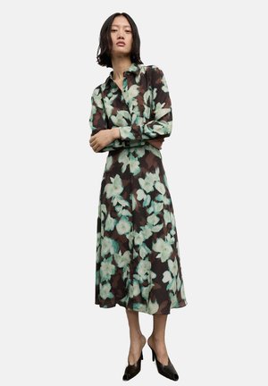 Vestido de botones con estampado floral que presenta un fondo marrón con grandes flores en tonos menta y blanco, hecho de una tela ligera. De longitud media y con mangas largas.