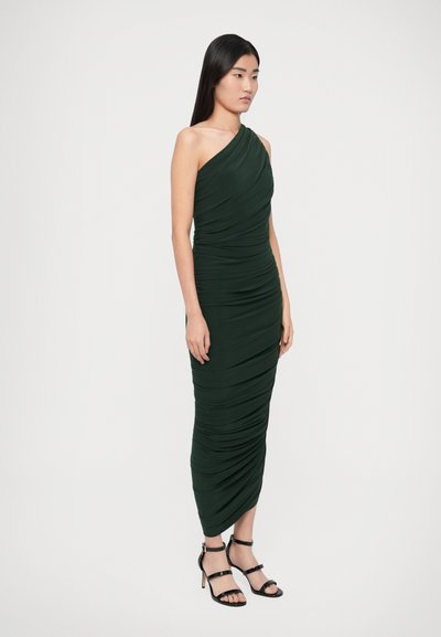 Zelené priliehavé šaty na jedno rameno s nariasenou textúrou, dĺžka po členky. Pohľad dopĺňajú čierne sandále s remienkami.