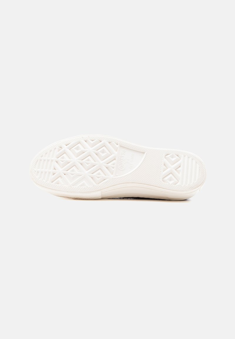 White sneaker sole shown from bottom with textured grip patterns and brand name embossed near arch area.