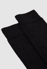 Schwarze gestrickte Socken mit gerippten Bündchen und einer glatten Textur, schlichtem Design und ohne sichtbare Muster oder Akzente.