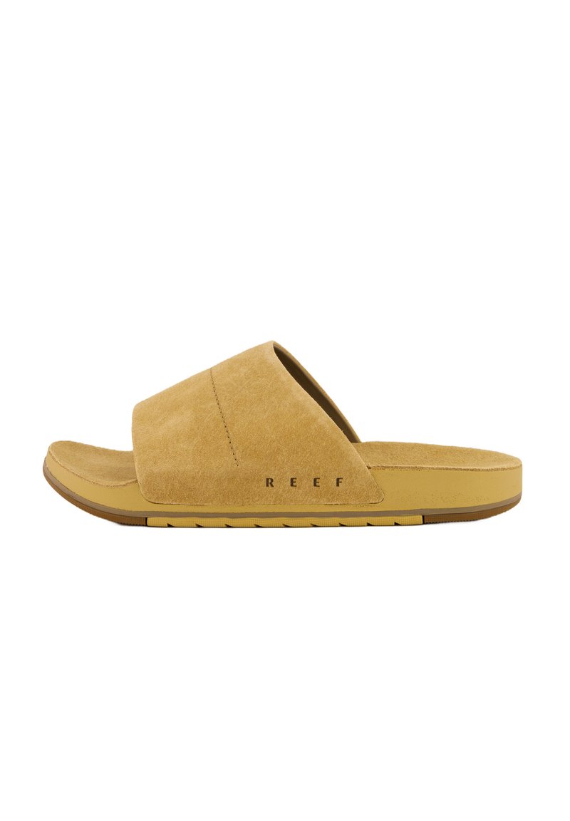 Sandale à glissière en daim beige clair avec un semelle intérieure rembourrée et une semelle en caoutchouc. Présente un design à bout ouvert et une marquage "REEF" bien visible.