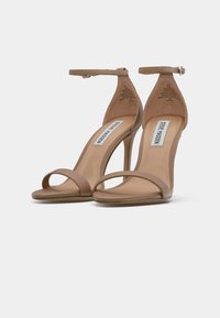 Beige-nude korkea kanta sandaalit minimalistisella muotoilulla, joissa on ohut nilkkaremmi, avoin varvasosa ja sileä pinta pohjalla.