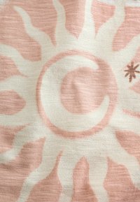 Hellrosa Stoff mit weißem Sonnenmotiv, das in der Mitte einen Halbmond und seitlich einen kleinen braunen Stern zeigt.