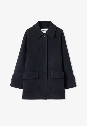 Schwarzer Wollmantel mit klassischem Kragen, Knopfverschluss vorne und zwei großen aufgesetzten Taschen. Texturierter Stoff, lockere Passform und Ärmel in Ellenbogenlänge.