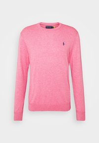 Maglione rosa a maglia con maniche lunghe, scollatura rotonda e polsini a costine. Presenta un piccolo emblema scuro sul petto sinistro. Texture morbida.