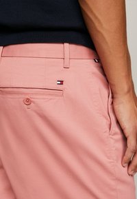 Pantalones cortos de algodón rosa con un bolsillo trasero con botón, pequeño logo bordado y bolsillos laterales, textura suave y corte entallado.