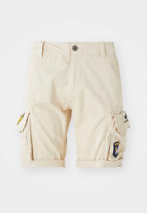 Shorts cargo beiges en coton, avec des ourlets roulés, des poches latérales et des patchs brodés sur la jambe. Coupe classique et design fonctionnel.