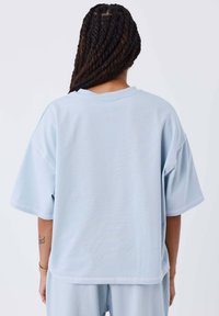Lichtblauwe sweatshirt met korte mouwen, een ontspannen pasvorm, ronde halslijn en zichtbare stikseldetails, gemaakt van zachte stof.