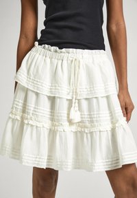 Gonna bianca a strati realizzata in tessuto leggero, con dettagli arricciati e una coulisse con nappine. Perfetta per l'abbigliamento estivo.