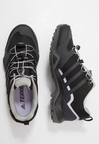 Zapatos de senderismo negros con tejido texturizado y suela de goma. Presentan detalles en gris, un sistema de cordones seguro y una puntera reforzada.