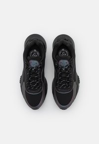 Chaussures de sport noires avec une tige en mesh texturé, des accents réfléchissants et des lacets à motifs, dotées d'une semelle amortie et d'un détail logo.