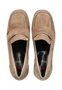 Mocasines de ante en color marrón claro, con punta redondeada, parte superior cosida y una correa sobre el empeine. Forro negro con un detalle en rojo.