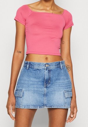 Rosa kurzes Oberteil mit kurzen Ärmeln, kombiniert mit einem blauen Denim-Minirock mit Fronttaschen und einem Knopfverschluss.