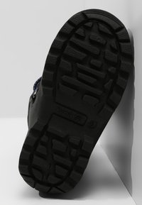 Black rubber boot sole with deep tread patterns, featuring the brand name "kamik" and size "8" embossed on the side.