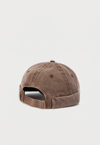 Καφέ ξεθωριασμένο καπέλο μπέιζμπολ, ορατό από πίσω, με ρυθμιζόμενο λουράκι και κουμπί καλυμμένο με ύφασμα στην κορυφή.