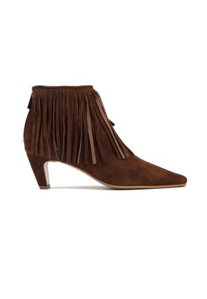 Brązowy botek zamszowy za kostkę z zaostrzonym noskiem, średniej wysokości obcasem typu koci pazur i długimi frędzlami wokół kostki.
