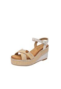 Sandale à semelle compensée avec des lanières tissées beiges et une semelle en cuir couleur sable. La plateforme présente des détails en jute tressé et une semelle en caoutchouc blanche.