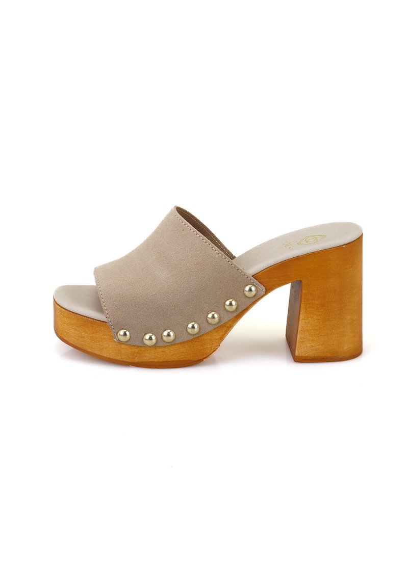 Beige suède open-toe slide sandaal met een brede band, houten blokhak en decoratieve metallic studs aan de zijkant. Zachte textuur.