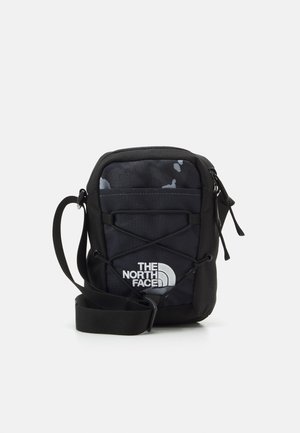 Kompaktowa czarna torba na ramię North Face z regulowanym paskiem, elastycznym sznurkiem z przodu i główną komorą zapinaną na zamek.