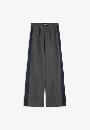 Pantalon gris à jambes larges avec ceinture élastique et bandes latérales foncées, portant une étiquette "Muse Project" sur la ceinture.