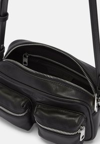 Borsa a tracolla in pelle nera con due tasche anteriori con cerniera, un compartimento principale con chiusura a zip e una finitura liscia e texturizzata.