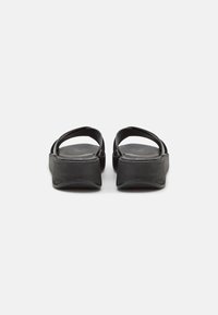 Sandali platform neri con tomaia in pelle liscia, design open toe e due fasce larghe. Suola bassa e testurizzata per aderenza e supporto.