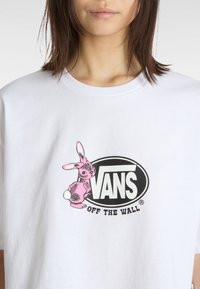 Hvid bomulds t-shirt med et sort oval logo med "VANS" og en pink kanin illustration, rund hals, korte ærmer.