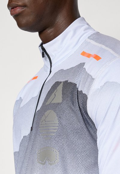 Chaqueta blanca con cremallera, que presenta un diseño texturizado, patrones abstractos en gris y acentos naranjas. Tiene un cuello alzado y una silueta ajustada.