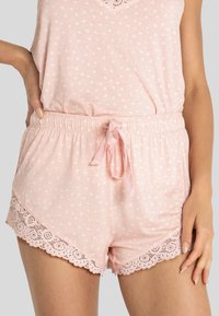 Ljusrosa pyjamas-set med stjärnmönster, spetskant på shortsen, resårmidja och detaljer med en satinrosett på dragsnöret.