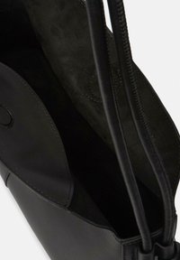 Czarna skórzana torba tote o gładkiej powierzchni, z podwójnymi uchwytami i miękkim zamszowym wnętrzem. Zapięcie na zamek i minimalistyczny design.