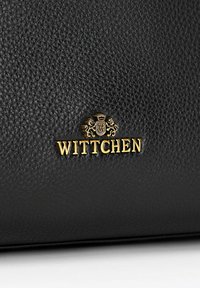 Borsa in pelle nera texturizzata con emblemma dorato e lettering "WITTCHEN", che evidenzia il suo design elegante e il materiale di alta qualità.