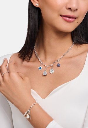 Silberne Halskette mit Anhängern in Stern-, Haus- und Kreisformen; blaue und silberne Akzente. Passendes silbernes Charm-Armband mit Perlen.