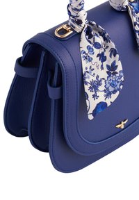 Navy blue leather handbag with flaps, gold hardware, and a floral scarf accent. Textured finish and structured shape with two side pockets.