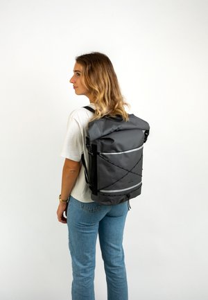 Rucsac gri tip roll-top cu curele ajustabile, accente reflectorizante și cordon bungee frontal, fabricat din material durabil, rezistent la apă.