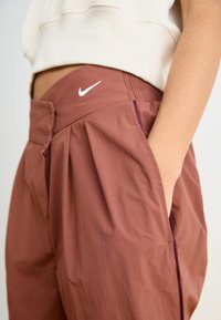 Rostfärgade sportshorts med avslappnad passform, elastisk midja och sidofickor. Har en liten vit Nike-logotyp framtill.