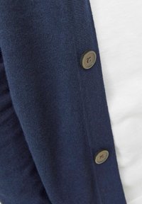 Cardigan blu navy realizzato in morbido tessuto a maglia, con chiusura a bottoni in cui è presente un bottone di colore neutro e un collo rotondo.