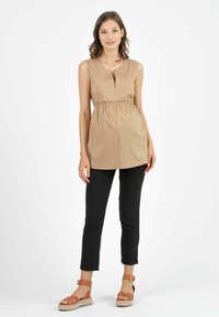Tan sleeveless top with pleats and a keyhole neckline, paired with black slim-fit pants and tan espadrille sandals.