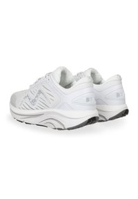 Zapatillas deportivas blancas con parte superior de malla texturizada, collar acolchado y suela de gruesa amortiguación. Presentan un patrón sutil en los lados y suela negra.