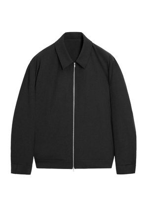 Veste noire à manches longues avec col pointu et fermeture éclair argentée sur le devant, présentée sur un fond blanc.